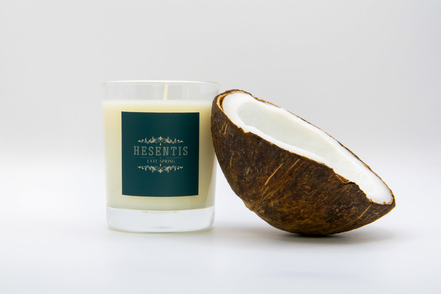 Hesentis Late Spring scented candle made from soy and coconut wax, presented next to a fresh coconut half on a neutral background.